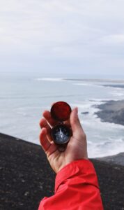 hand holding compass near coastline