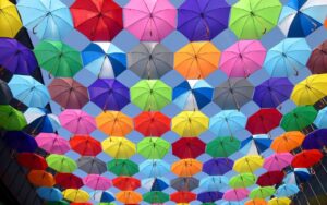yellow blue red pink purple green multicolored open umbrellas hanging on strings under blue sky