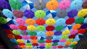 yellow blue red pink purple green multicolored open umbrellas hanging on strings under blue sky